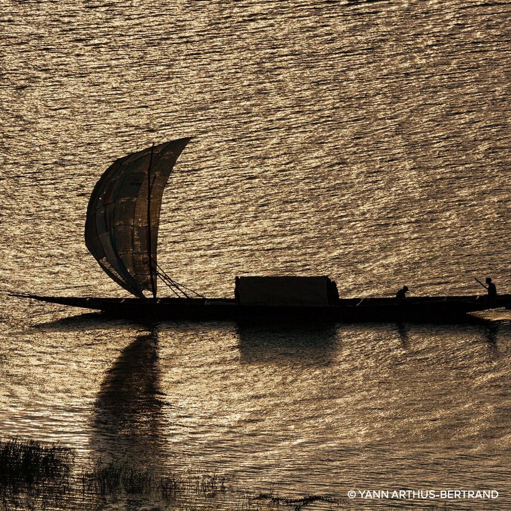 Silhouette di una barca a vela su acqua scintillante. Luce solare.