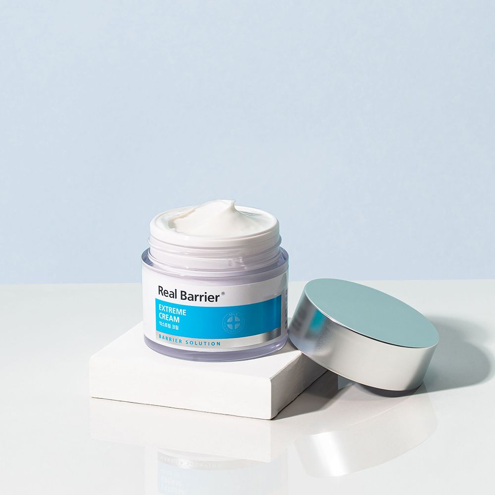 Vasetto di crema aperto su piedistallo bianco. Coperchio argentato accanto. Scritta: Real Barrier, Extreme Cream.