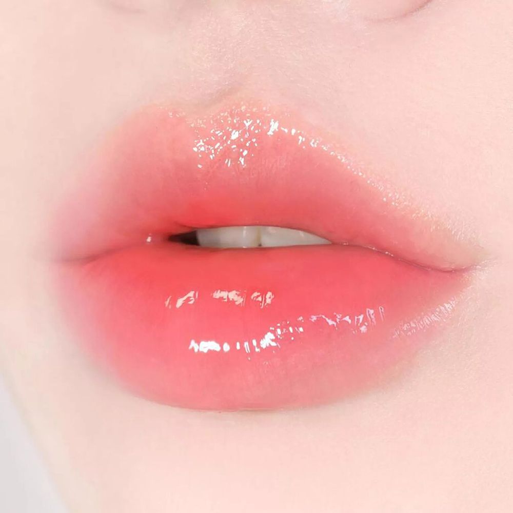 Primo piano di labbra rosa lucide. Le labbra sono leggermente socchiuse.