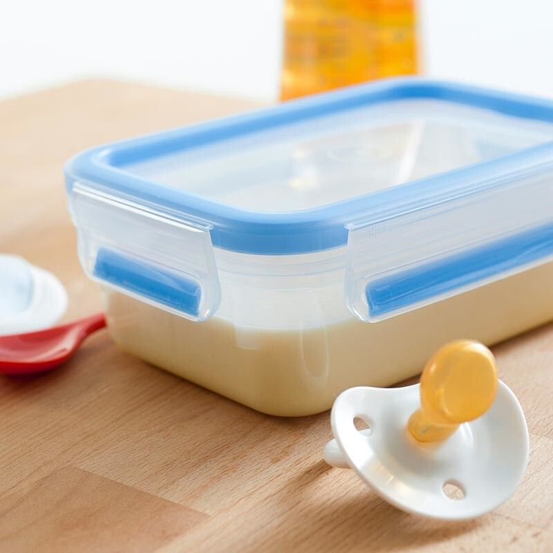 Contenitore rettangolare con coperchio blu e liquido cremoso. Accanto ciuccio e cucchiaio.