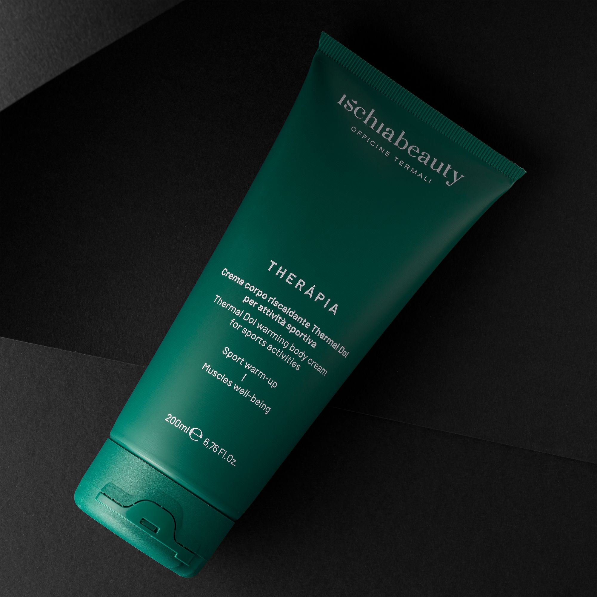 Tubo verde con testo. Ischiabeauty, THERAPIA, crema per sport. 200ml. Sfondo nero.