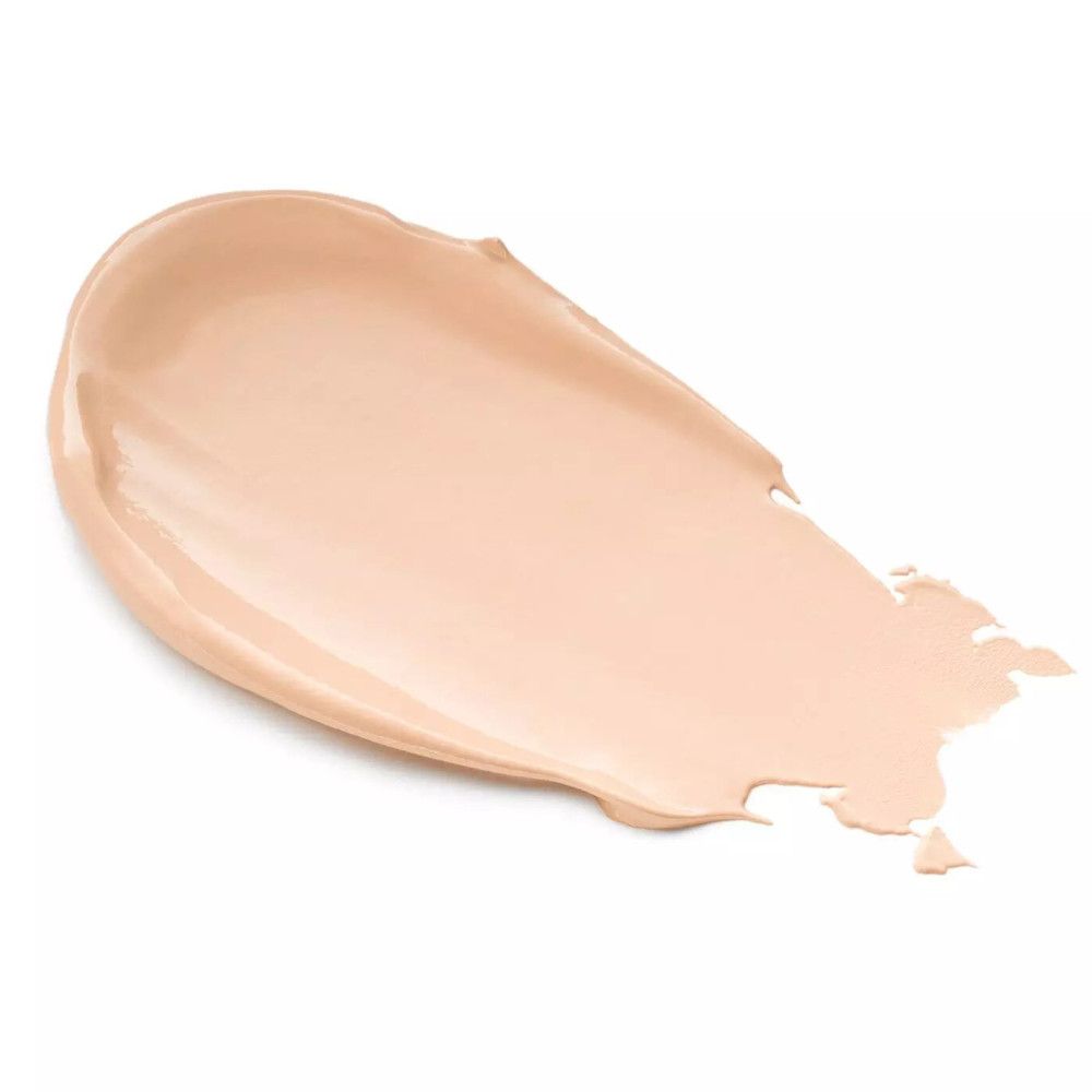 Una striscia di crema correttiva color crema su sfondo bianco. La consistenza è liscia e leggermente lucida.