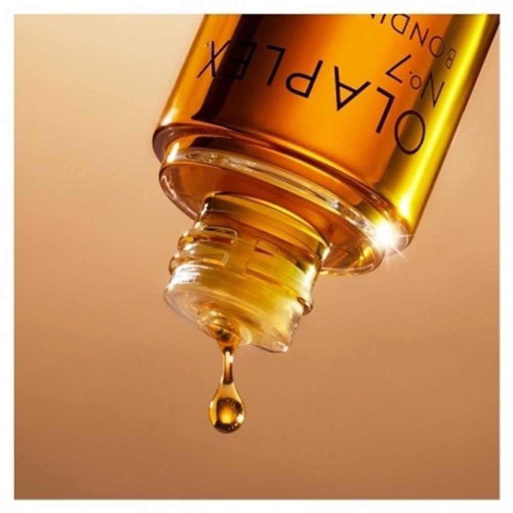 Olio Olaplex No.7 Bonding, goccia. Olio dorato che gocciola da una bottiglia. Scritta: Olaplex No.7 Bonding Oil.