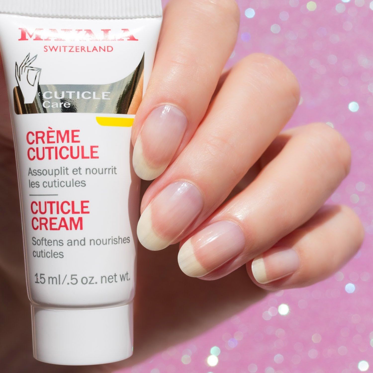 Tubo 'Crème Cuticule' accanto a una mano con unghie smaltate. Scritta 'Mavala'. Tubo di crema con accento giallo.