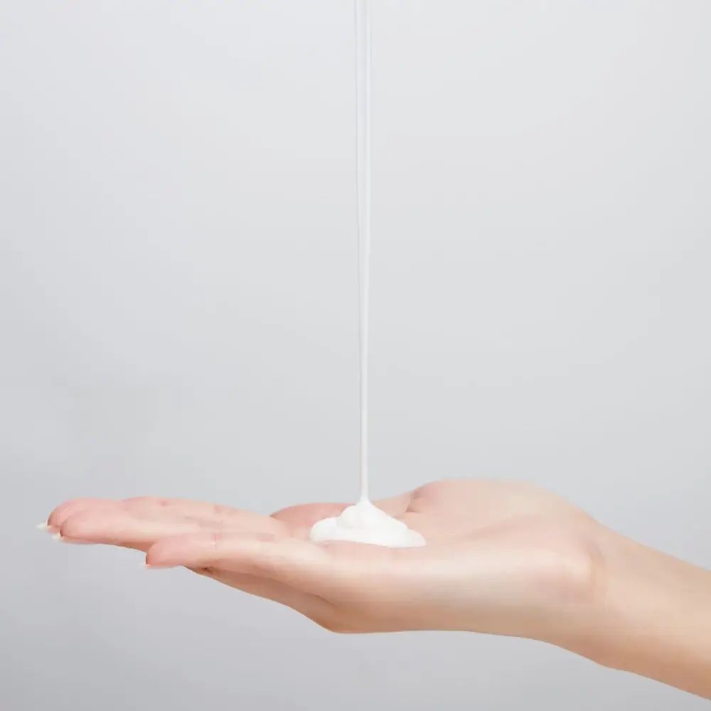 Crema versata da una mano all'altra. Liquido bianco.