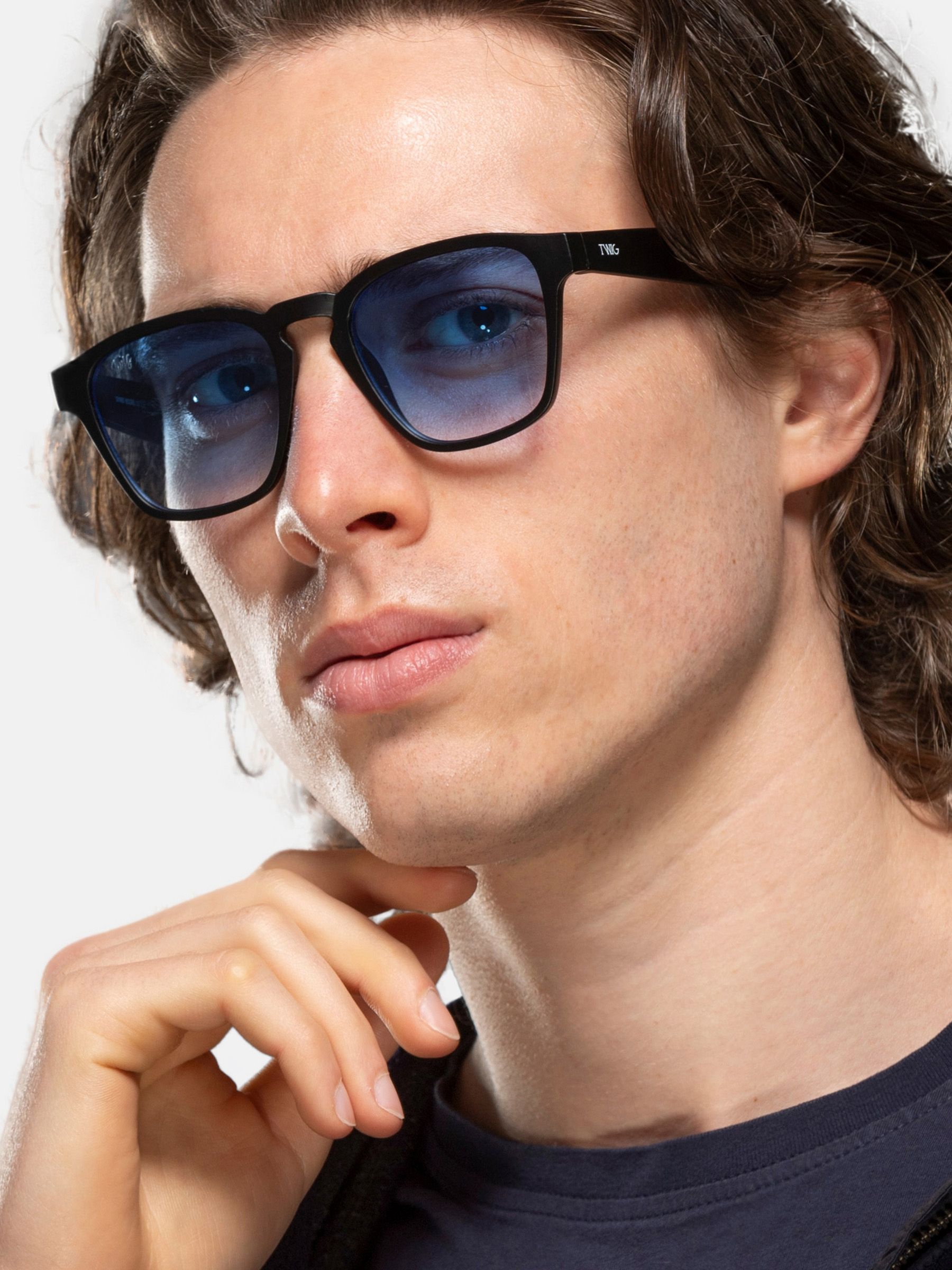 Uomo con occhiali da sole neri con lenti blu. Forma quadrata.