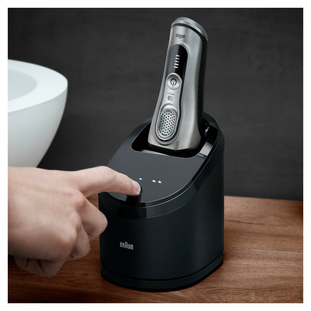 Rasoio nella stazione di ricarica nera. Dito che tocca la stazione. Logo "Braun".