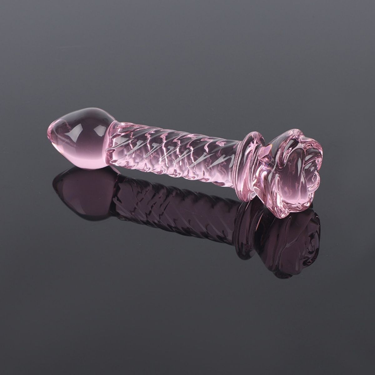 Bacchetta di vetro rosa, superficie scanalata, impugnatura a fiore. Su sfondo scuro e lucido.