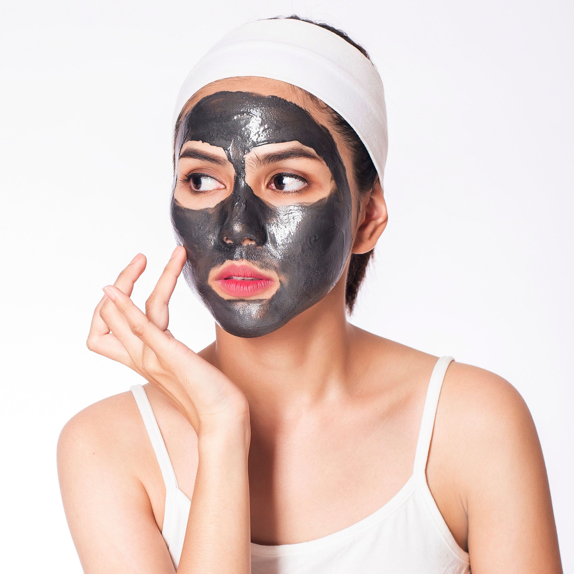 Donna con maschera viso e fascia. Viso coperto da maschera, tocca la pelle.