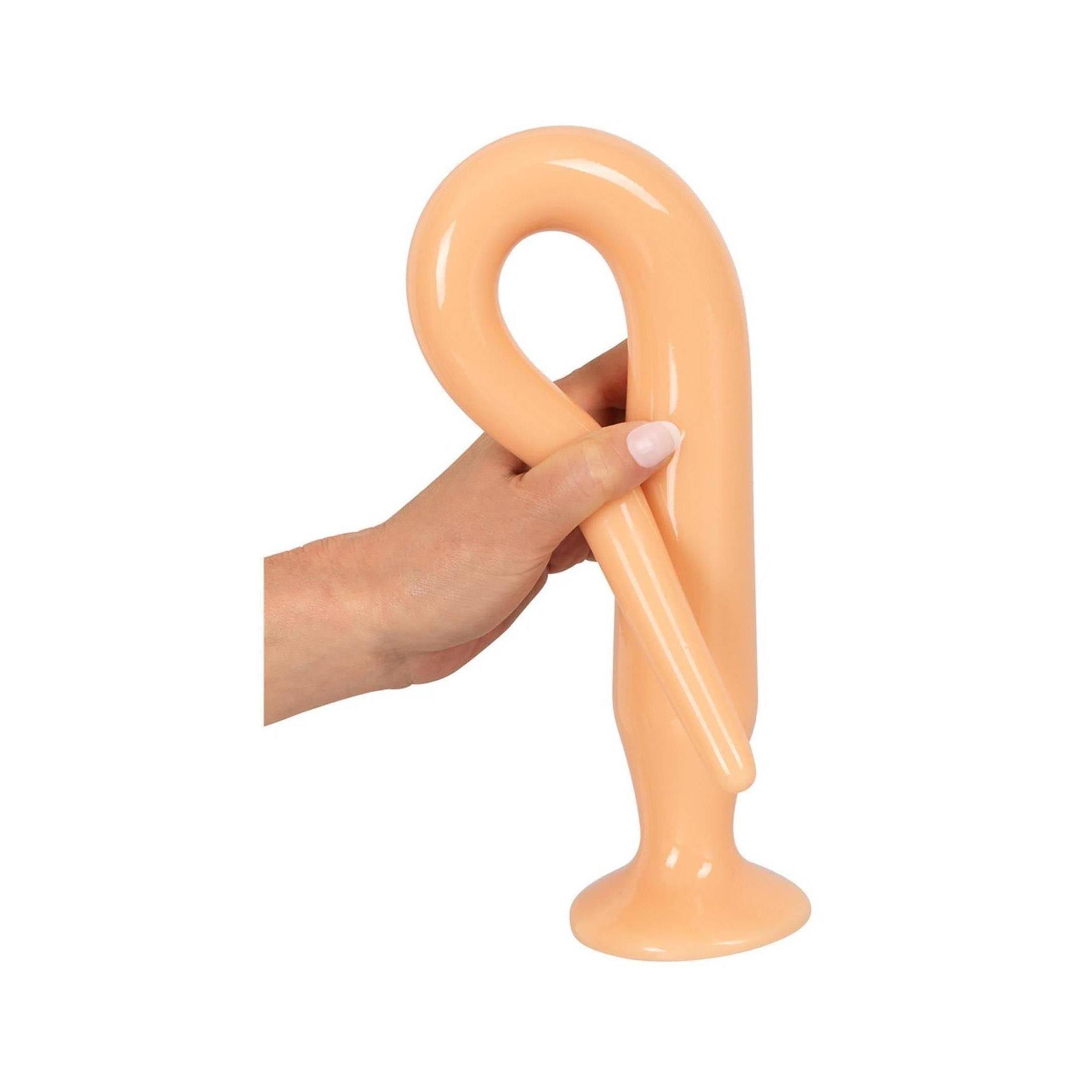 Un modello di plug anale marrone chiaro, tenuto in mano. Il prodotto è piegato a forma di U.