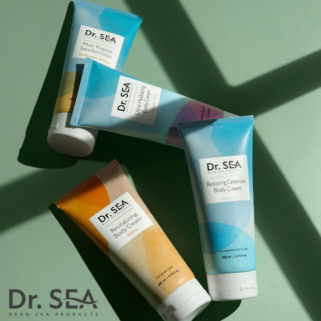 Quattro tubi di crema corpo DR. SEA. Diversi design: Ultra Idratante, Restauro Ceramidi, Crema Corpo Rivitalizzante. Sfondo verde.