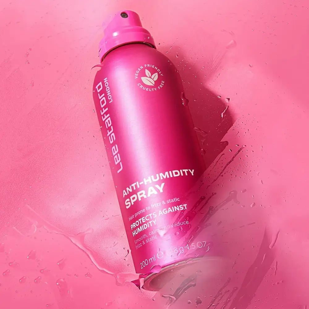 Flacone spray rosa Lee Stafford Anti-Humidity. Vegano e cruelty-free. Su sfondo rosa con acqua.