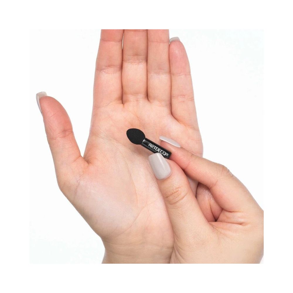 Mini applicatore ombretto. Applicatore nero con logo ARTDECO, tenuto in mano.
