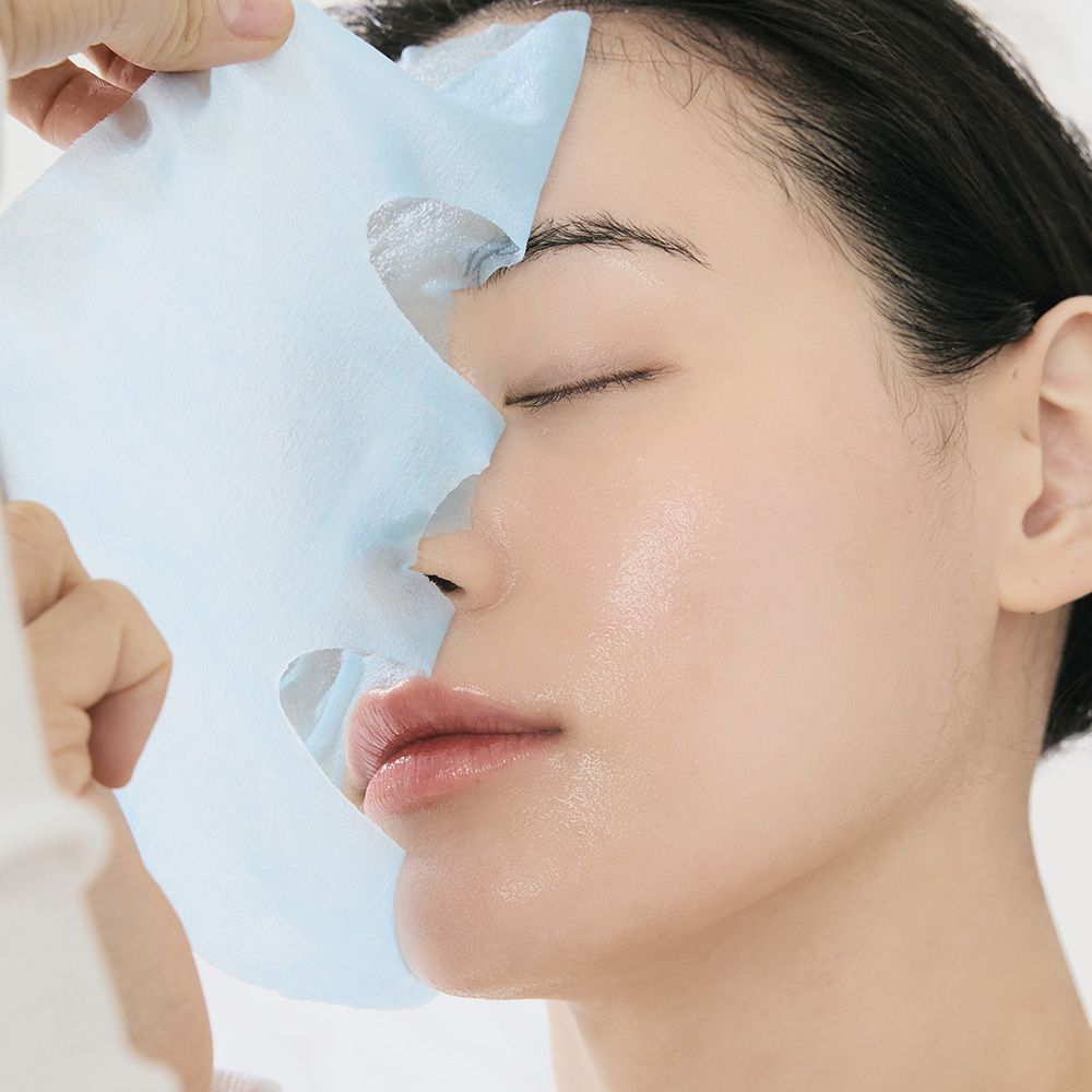 Una donna si applica una maschera in tessuto blu sul viso.