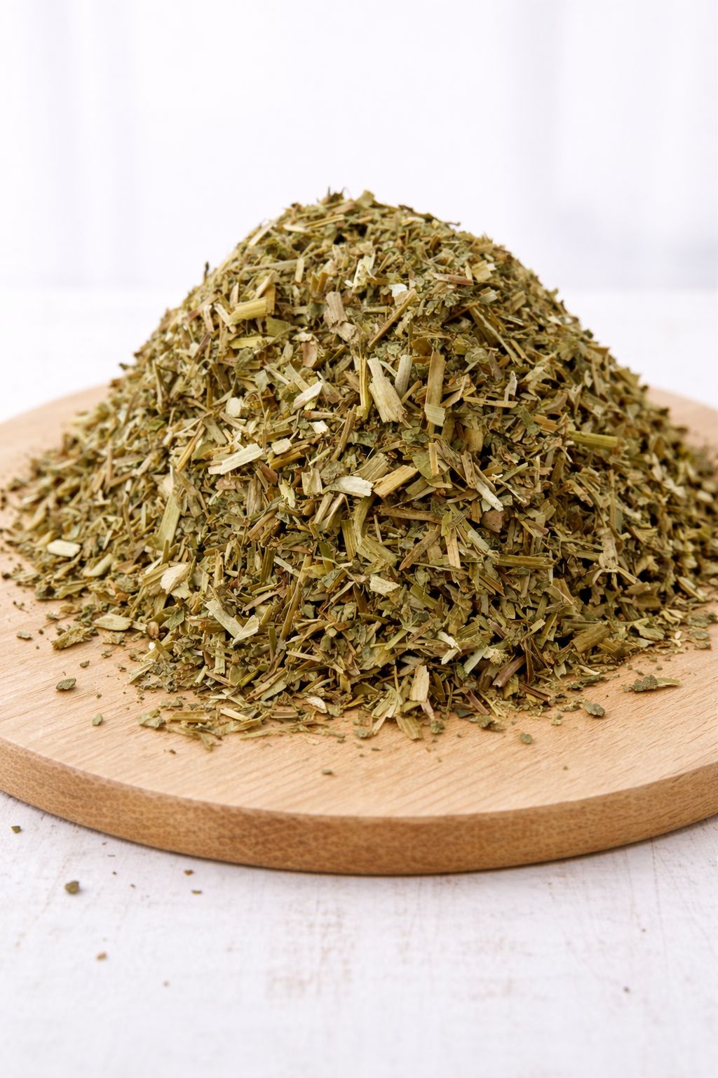 Mucchio di erbe secche verdi su un tagliere di legno. Le erbe sono tagliate grossolanamente.