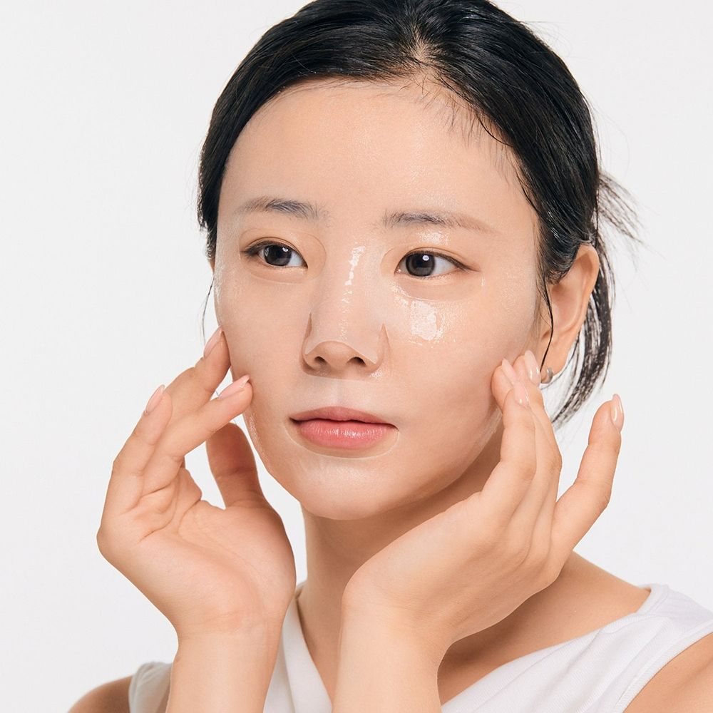 Una donna con una maschera in tessuto sul viso. Si tocca il viso con entrambe le mani.