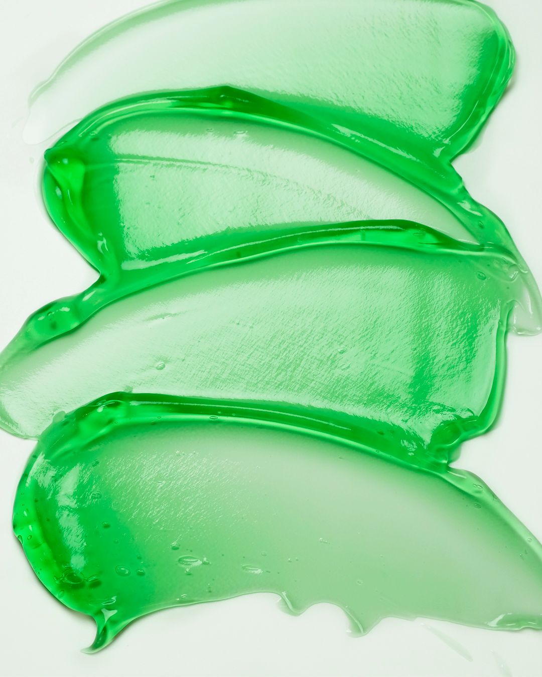 Tracce di gel verde su sfondo bianco. La consistenza è visibile.