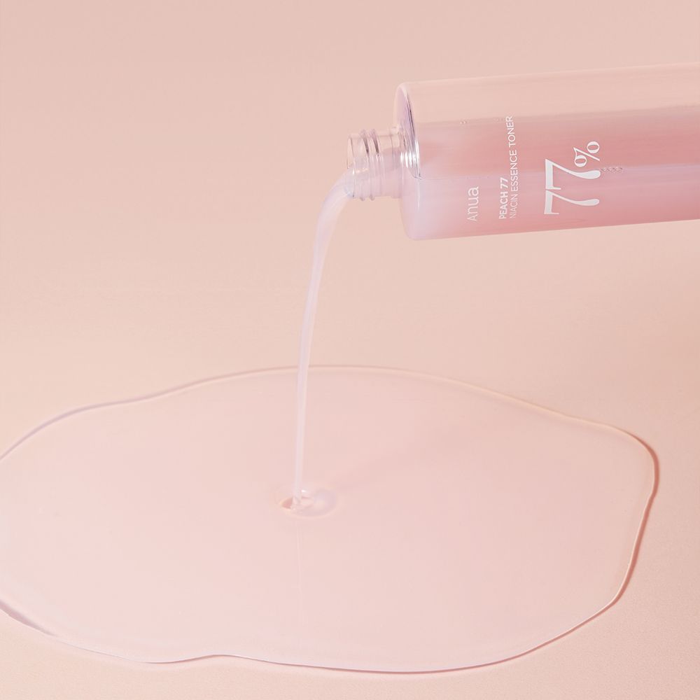 Il tonico essenza niacinamide ANUA Peach 77% viene versato da una bottiglia su una superficie.