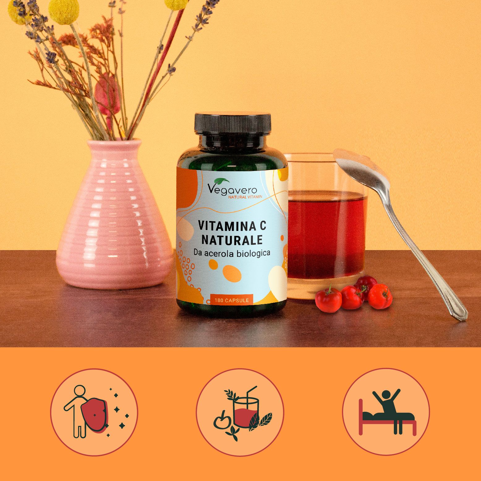 Flacone di vitamina C, bicchiere con liquido, cucchiaio, fiori, ciliegie. Scritta: VITAMINA C NATURALE. Logo Vegavaro.
