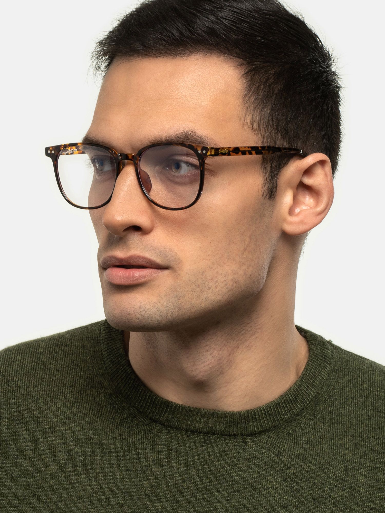 Uomo con occhiali marroni a fantasia tartarugata. Lenti rettangolari, aste scure. Maglione verde.