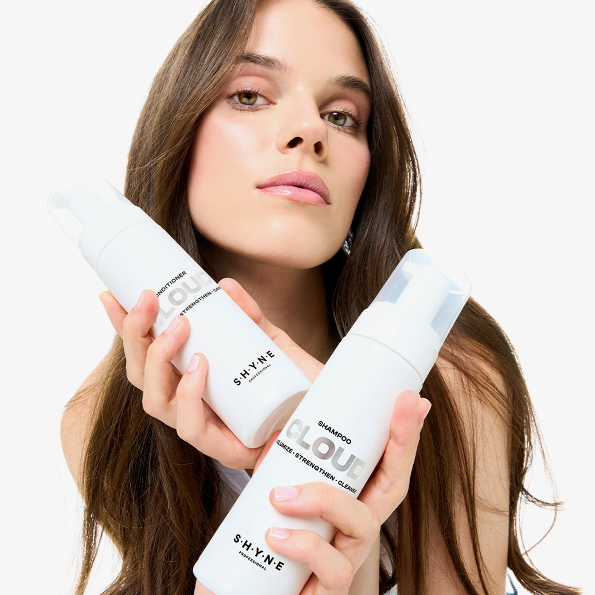 Donna tiene due flaconi bianchi: SHYNE Cloud Conditioner e Shampoo. Con erogatore.