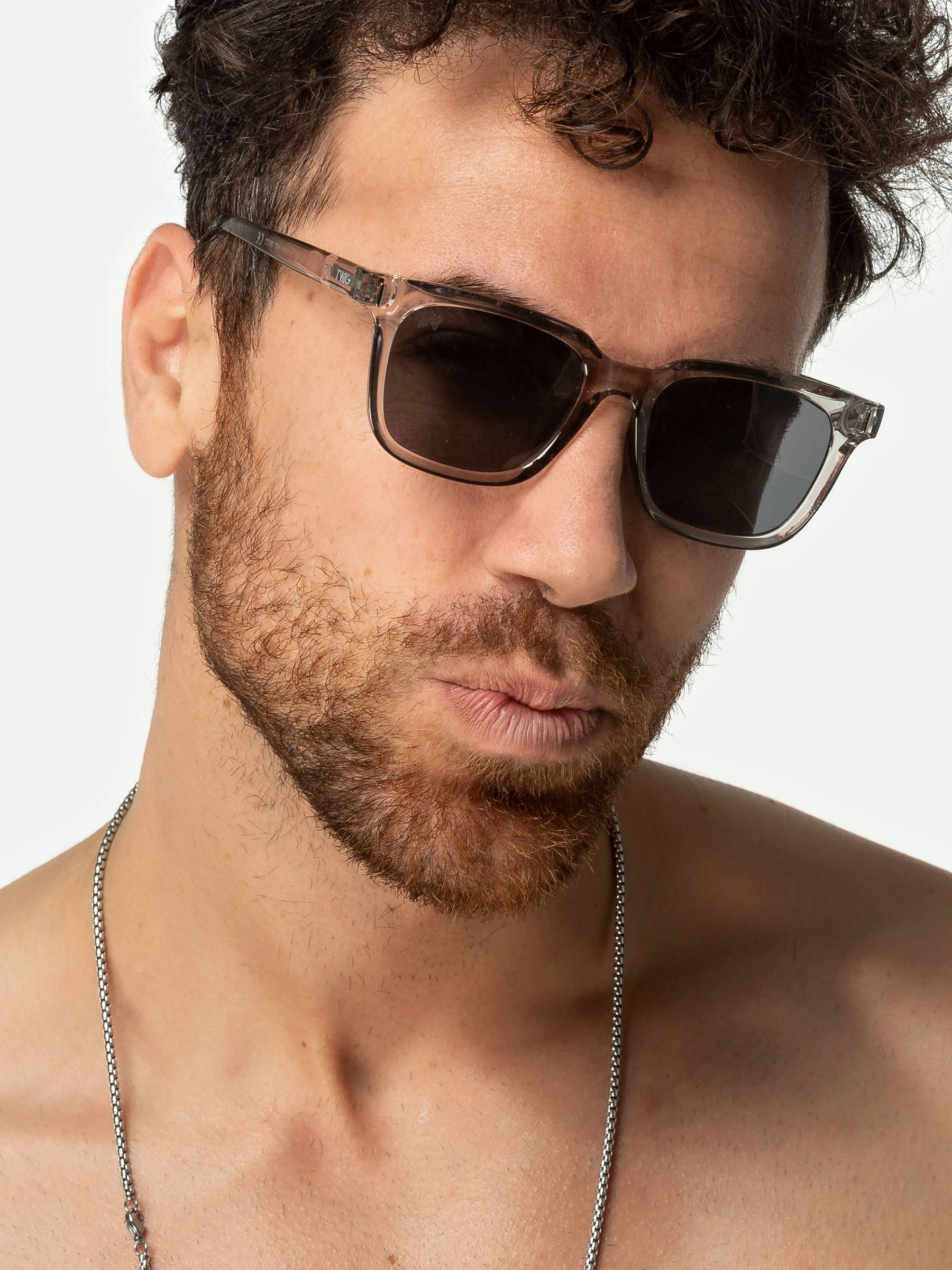 Uomo con occhiali da sole Twig. Montatura grigia, lenti rettangolari. Primo piano.