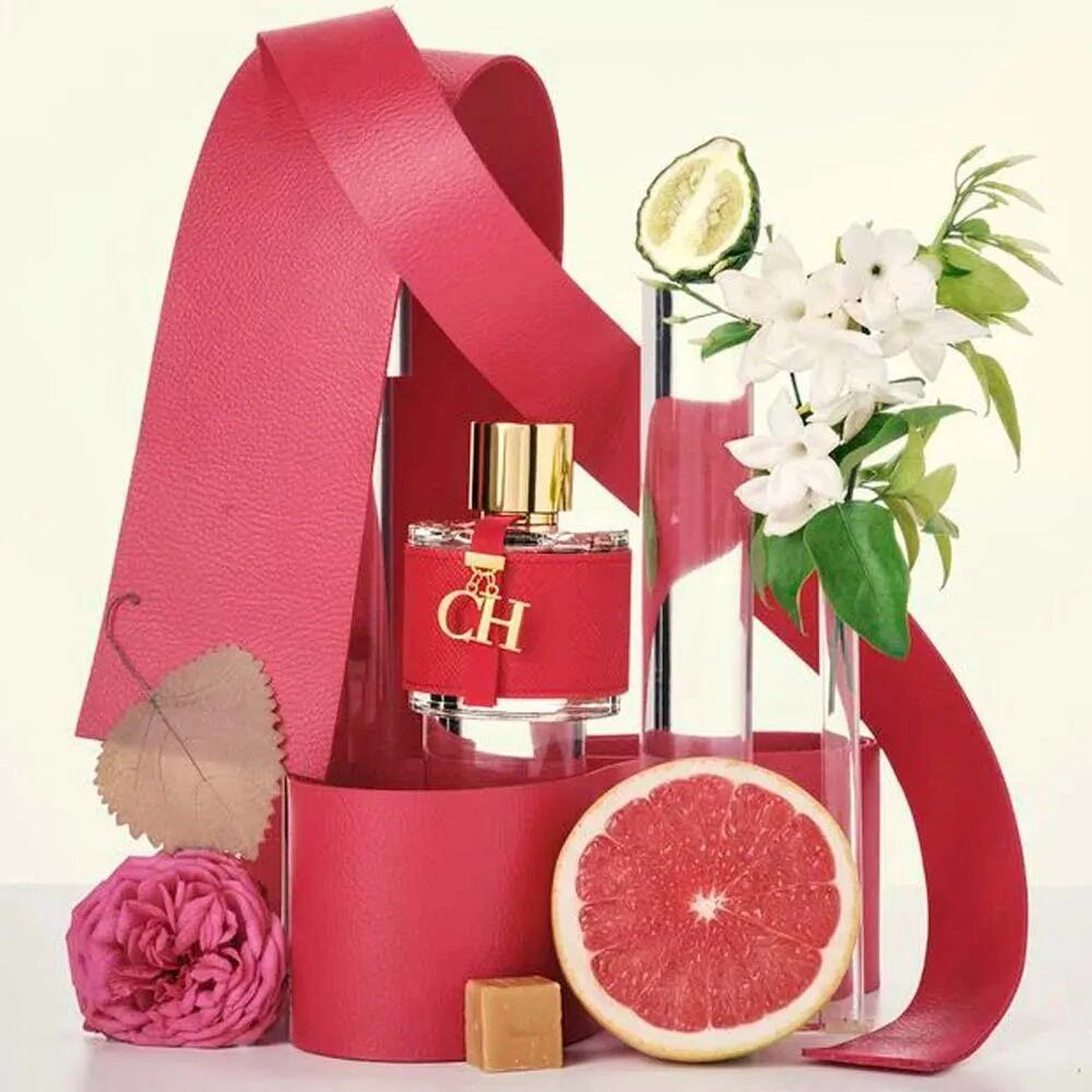 Flacone rosso con tappo dorato e ciondolo. Decorazione con nastri rossi, fiori, pompelmo e lime.