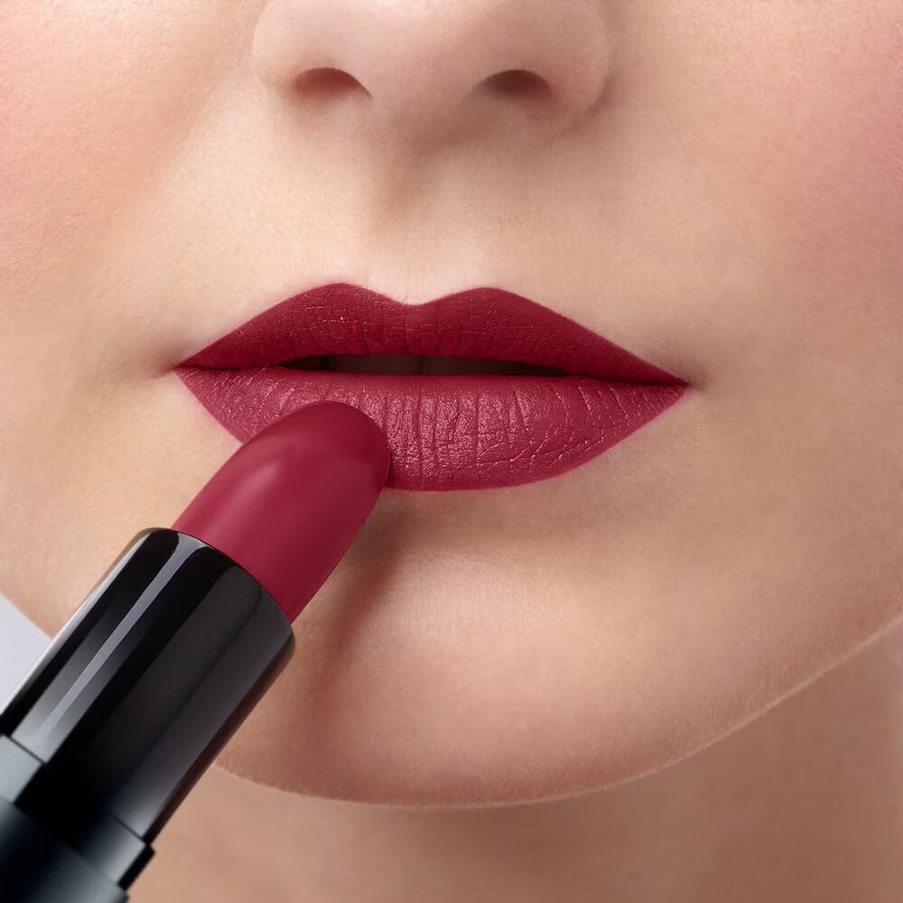 Una persona applica un rossetto rosso sulle labbra.