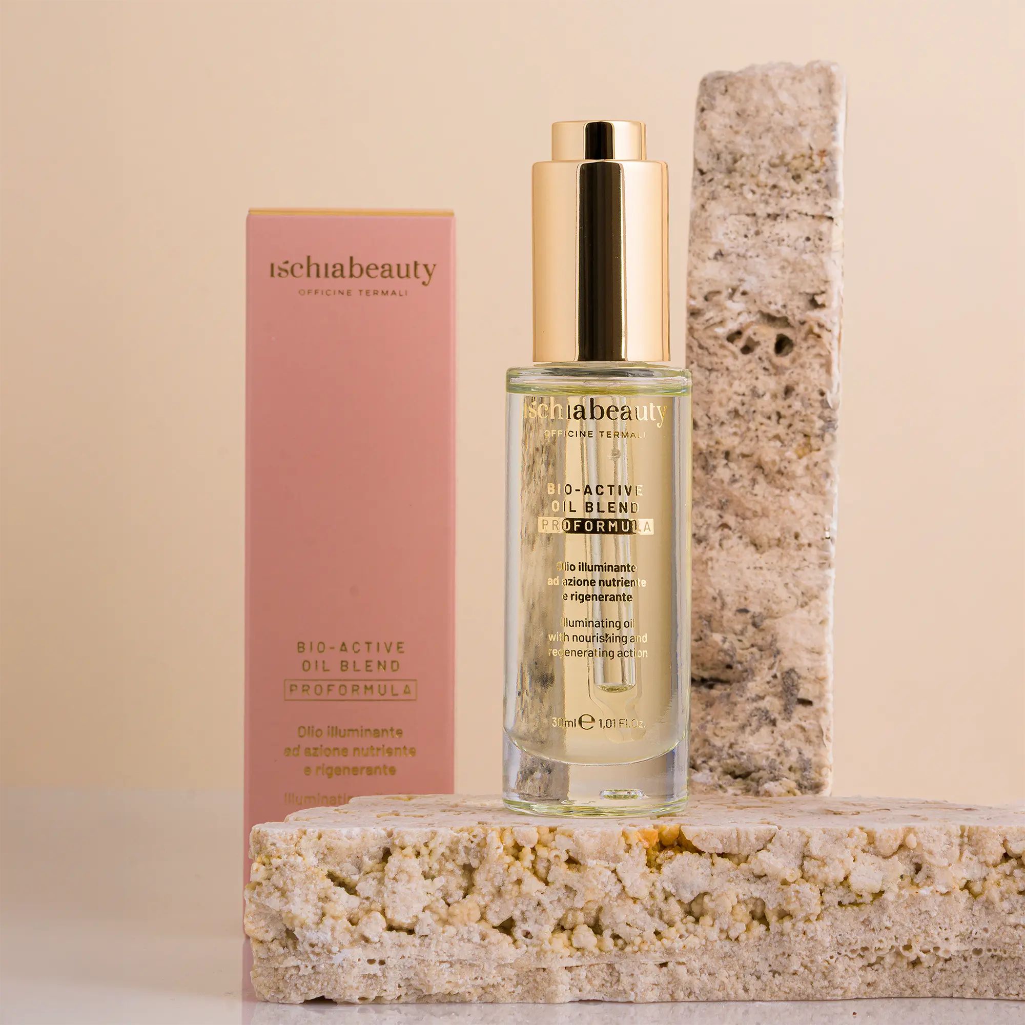 Flacone con tappo dorato e confezione rosa. Scritta: ischiabeauty, BIO-ACTIVI OIL BLEND. Su blocchi di pietra.