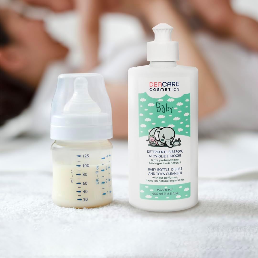 Biberon con latte e detergente DEACARE Baby. Flacone bianco con dosatore, testo e illustrazioni. Su superficie bianca.