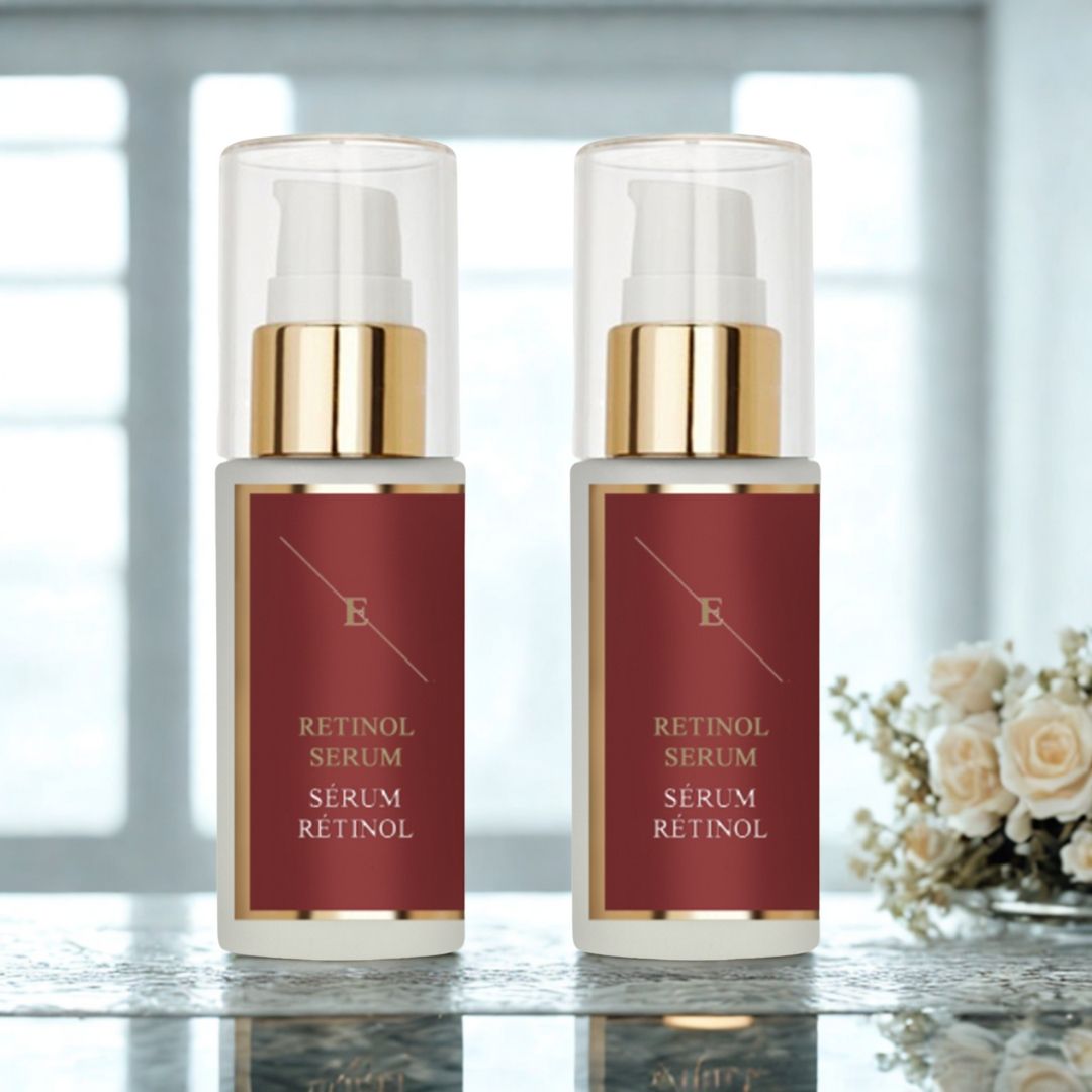 Due flaconi di siero con dosatore a pompa. Etichette rosse con testo bianco: RETINOL SERUM, RETINOL sotto. Dettagli dorati. Su tavolo con fiori.