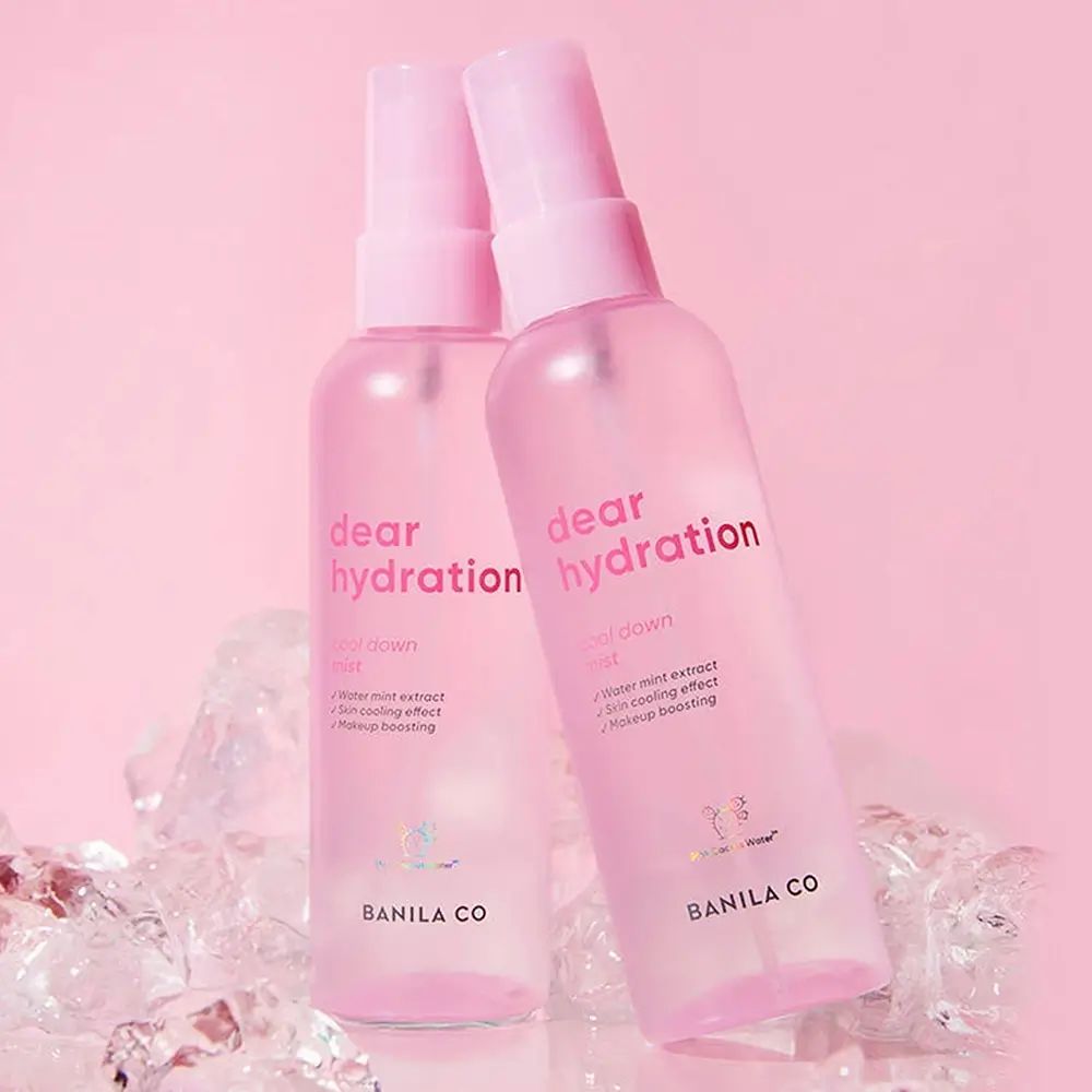 Due flaconi spray rosa con "dear hydration mist" e "BANILA CO" su cubetti di ghiaccio.
