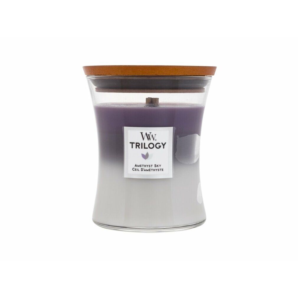 Candela a tre colori con stoppino in legno, in contenitore di vetro con coperchio. Etichetta con logo e testo: Trilogy, Amethyst Sky, Ciel d'Améthyste.