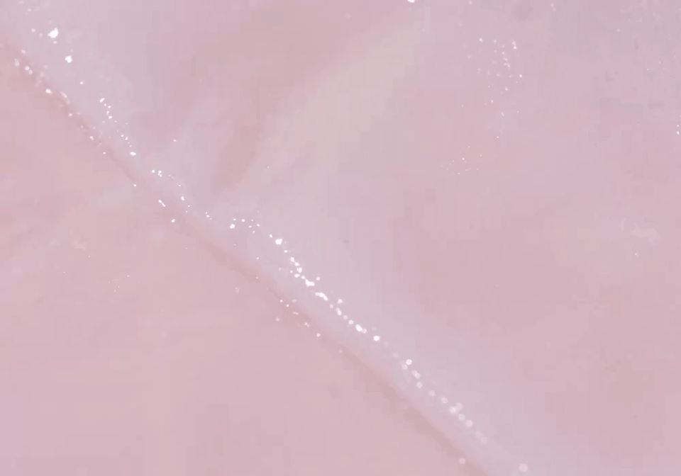 Primo piano di una maschera in tessuto rosa umida con particelle scintillanti.
