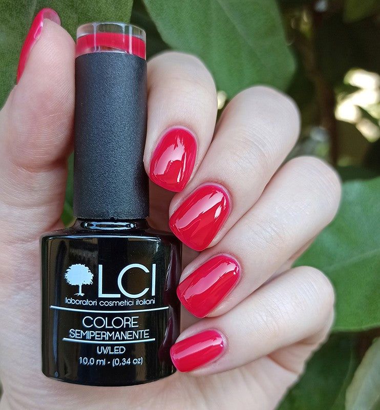 Flacone nero di smalto accanto a una mano con unghie rosse smaltate. Testo: LCI, COLORE SEMIPERMANENTE, UVLED.