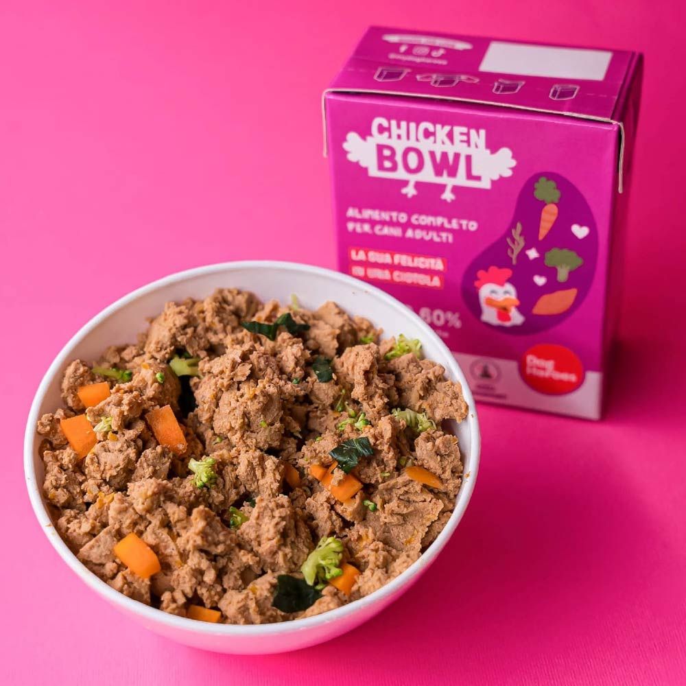 Cibo per cani "Chicken Bowl" in una ciotola. Confezione rosa sullo sfondo. Testo: "Alimento completo per cani adulti".