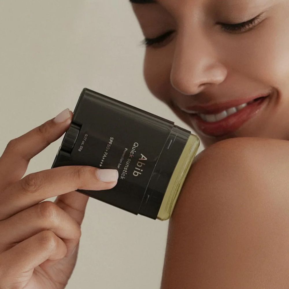 Una donna applica l'ABIB Quick Sunstick Protection Bar sulla spalla.
