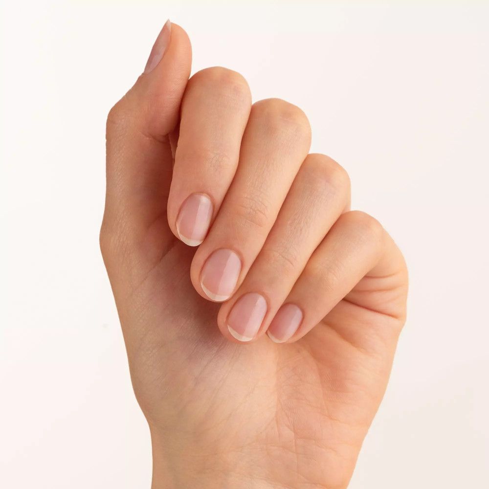 Mano con cinque unghie smaltate. Le unghie sono corte e di forma ovale. Lo smalto è trasparente.