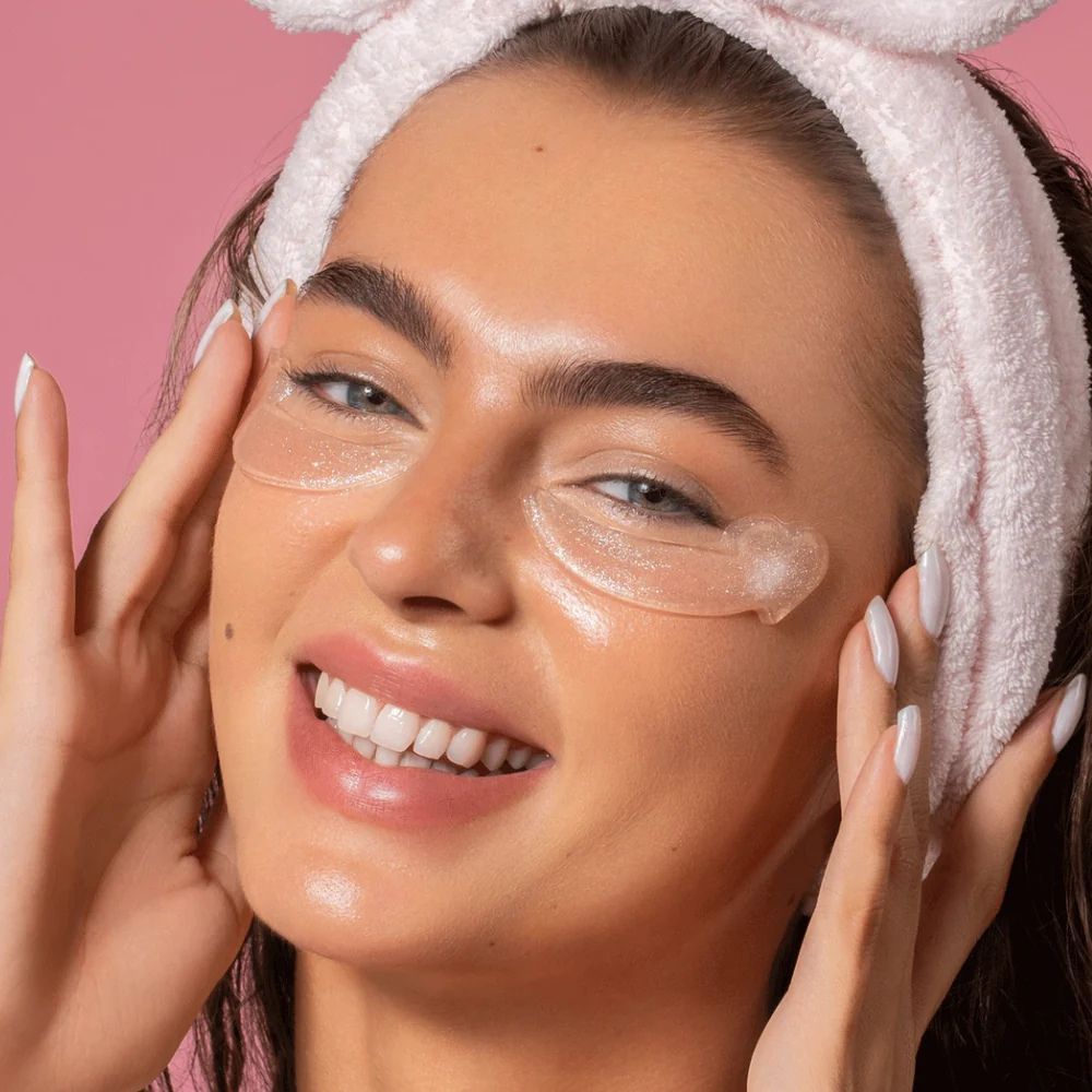 Donna con cuscinetti per occhi e fascia rosa. Si tocca gli occhi. Cuscinetti per occhi visibili.