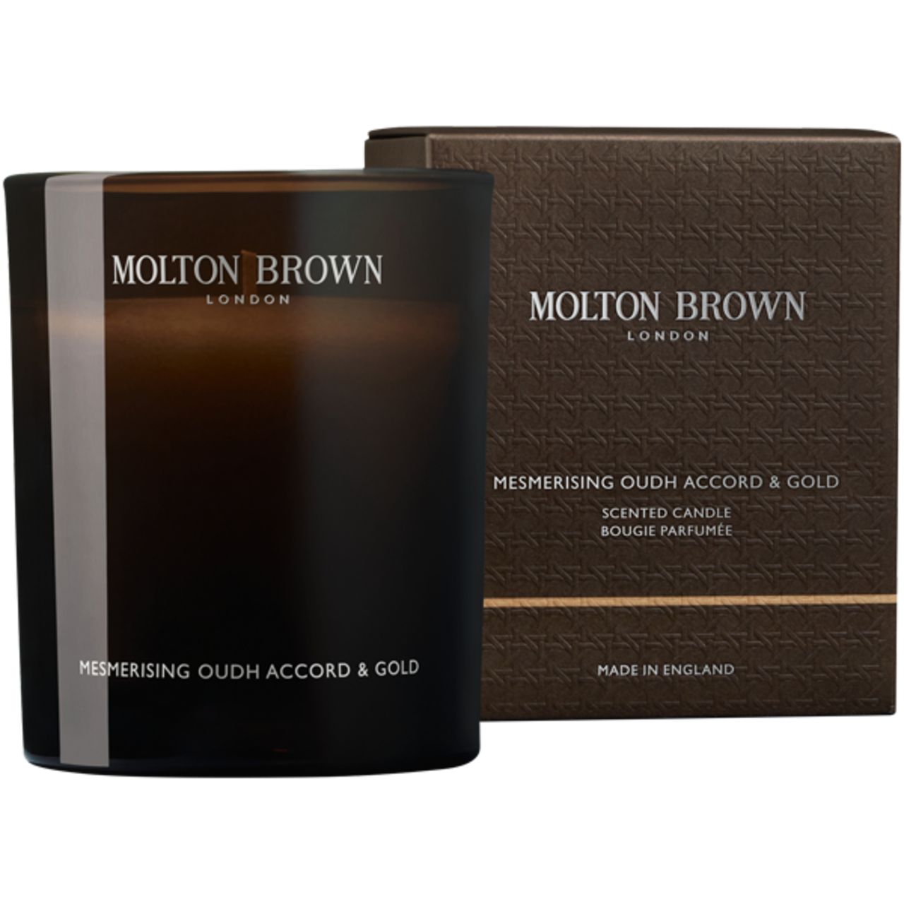 Candela profumata e confezione. Candela in vetro scuro con striscia bianca. Confezione con scritta: Molton Brown London.
