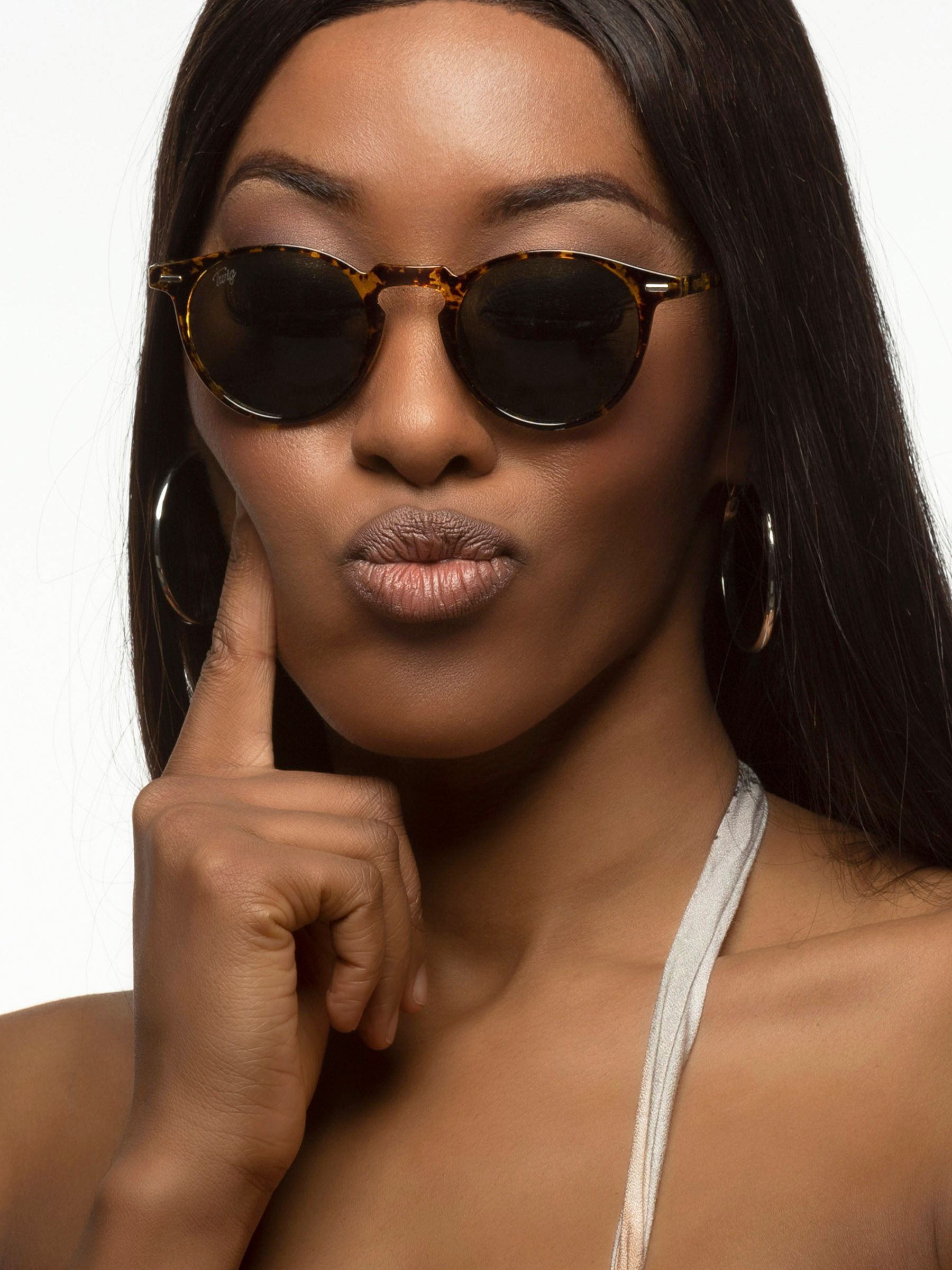 Donna con occhiali da sole. Occhiali rotondi, montatura marrone maculata, lenti verdi.