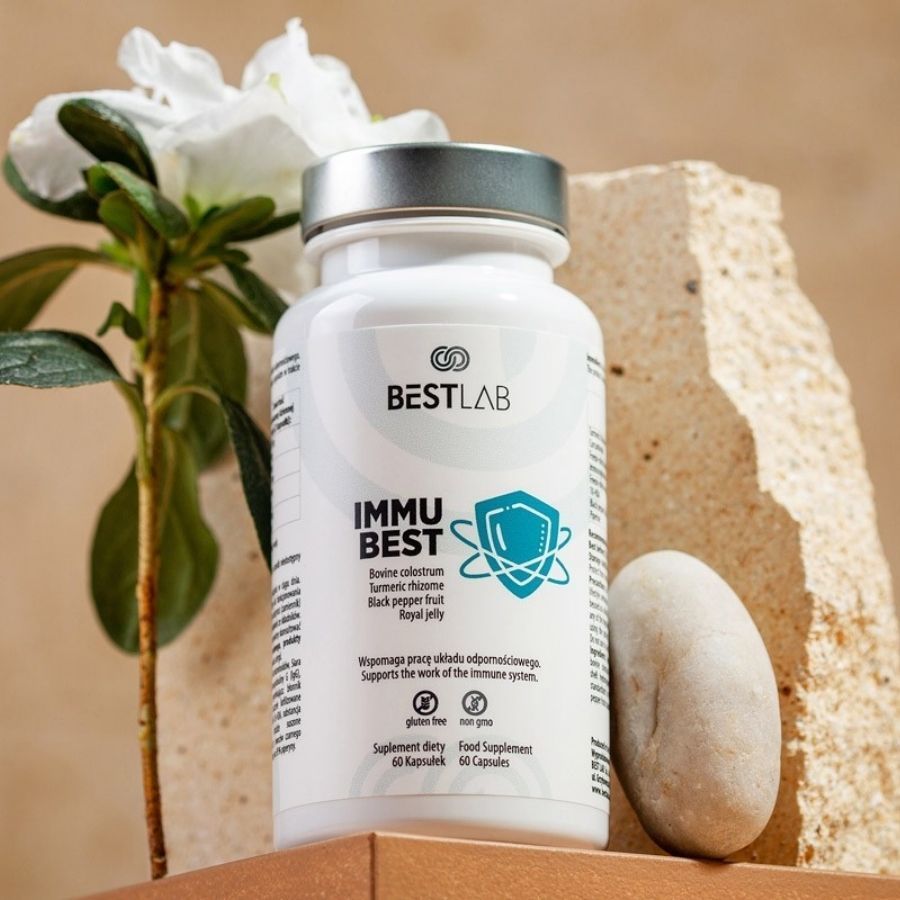 Flacone bianco di capsule, accanto a pietra e pianta. Scritta: BEST LAB, IMMU BEST. Contiene colostro, curcuma, pepe nero e pappa reale.