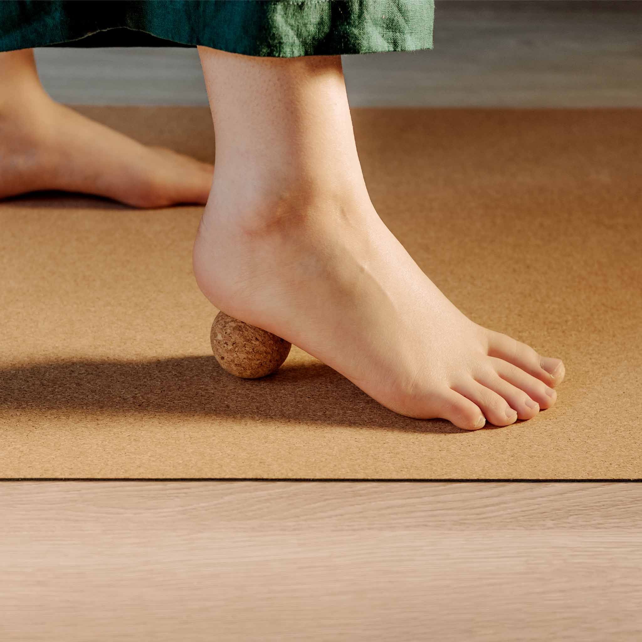 Persona usa una sfera in sughero sotto il piede. Su un tappetino. Sughero naturale.
