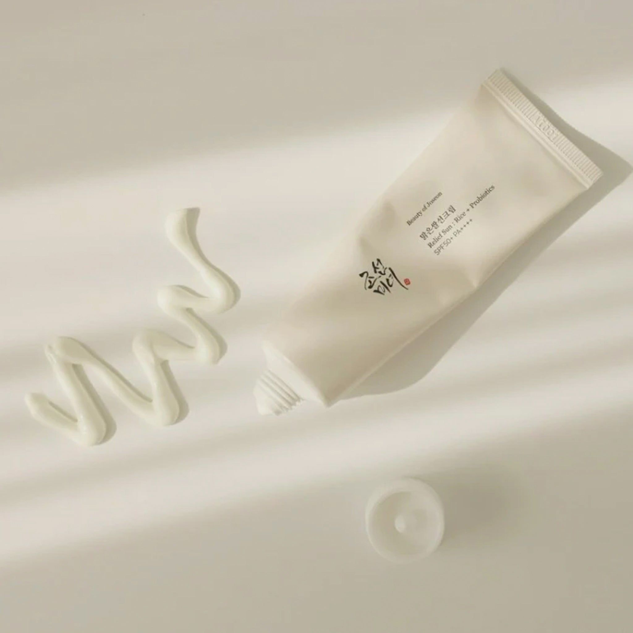 Un tubetto di crema e una goccia di crema accanto. Testo sul tubetto.