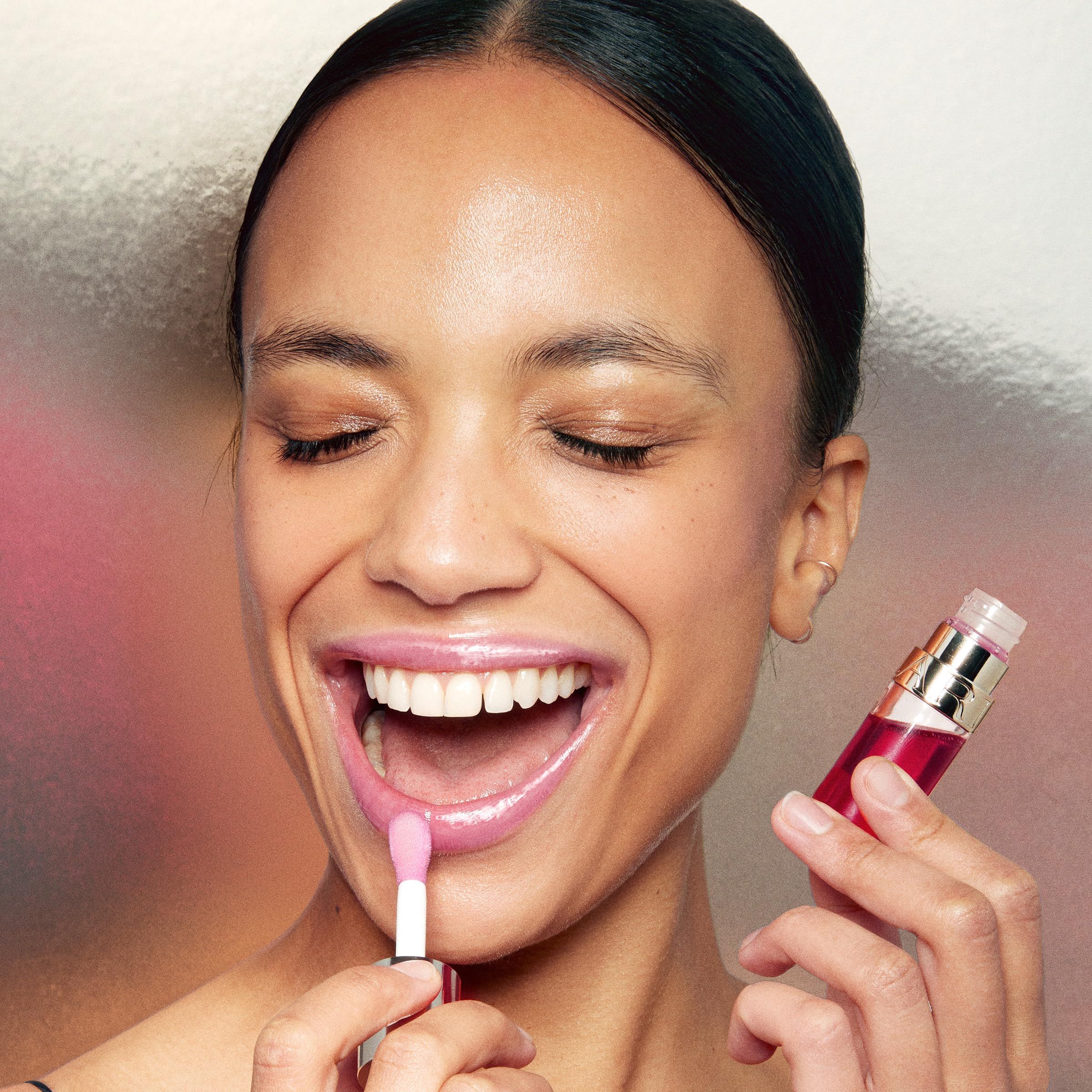 Donna con bocca aperta, applica olio per labbra. Applicatore rossetto in mano.