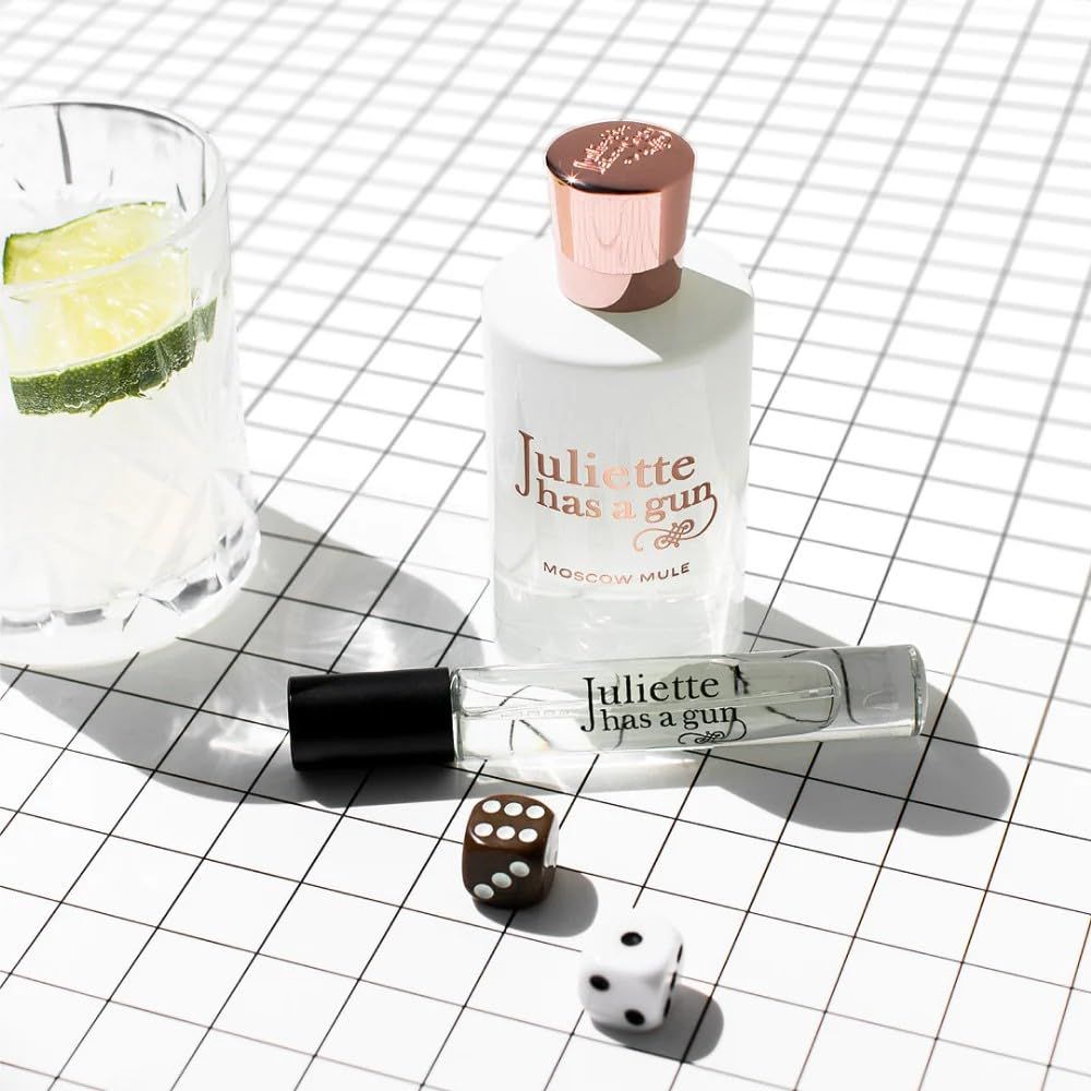 Flacone di profumo, roll-on, dadi e bicchiere con lime. Scritta: Juliette has a gun Moscow Mule.
