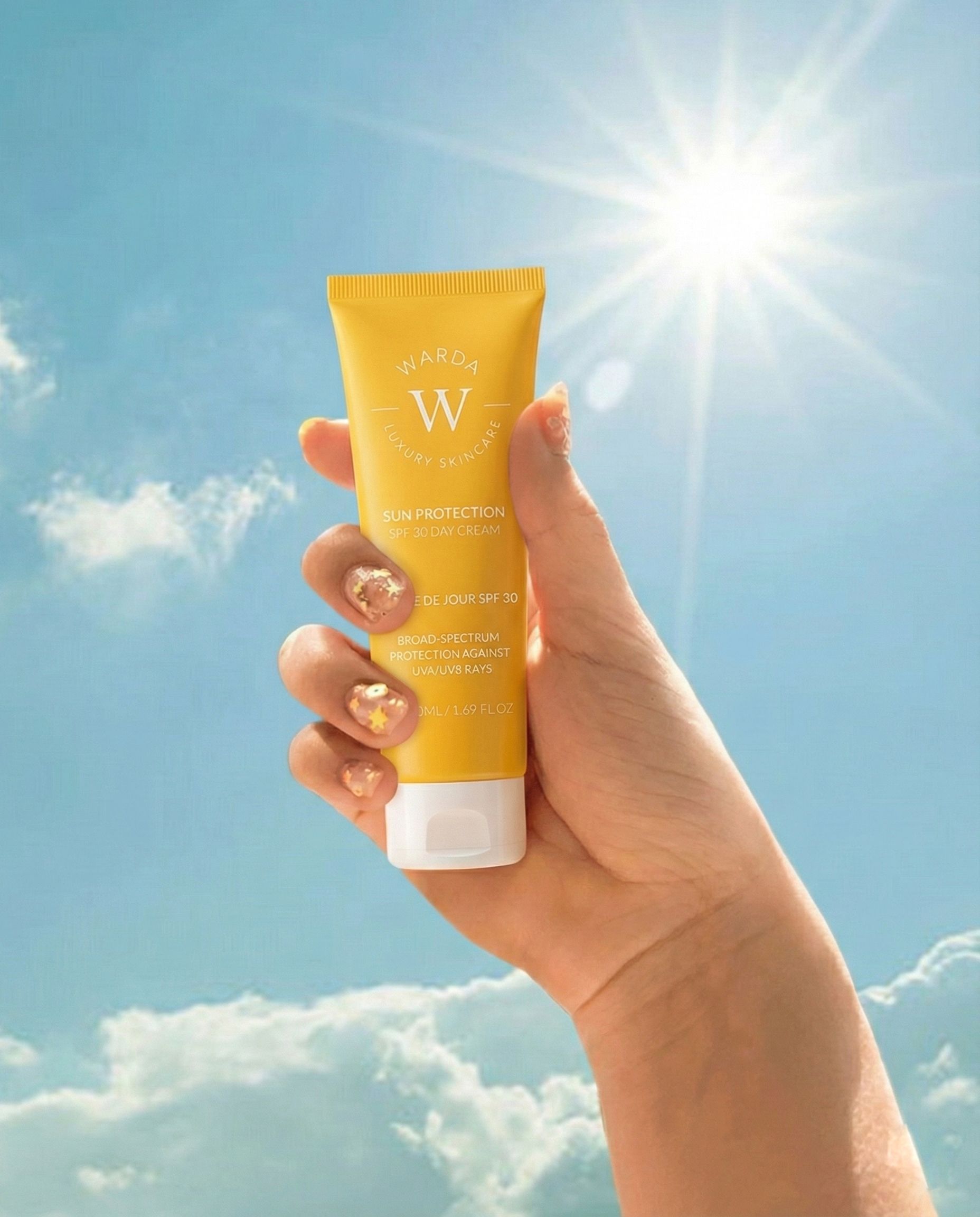 Tubo giallo in mano, davanti a cielo blu e sole. Scritta: Sun Protection SPF 30 Day Cream. Marchio: Warda.