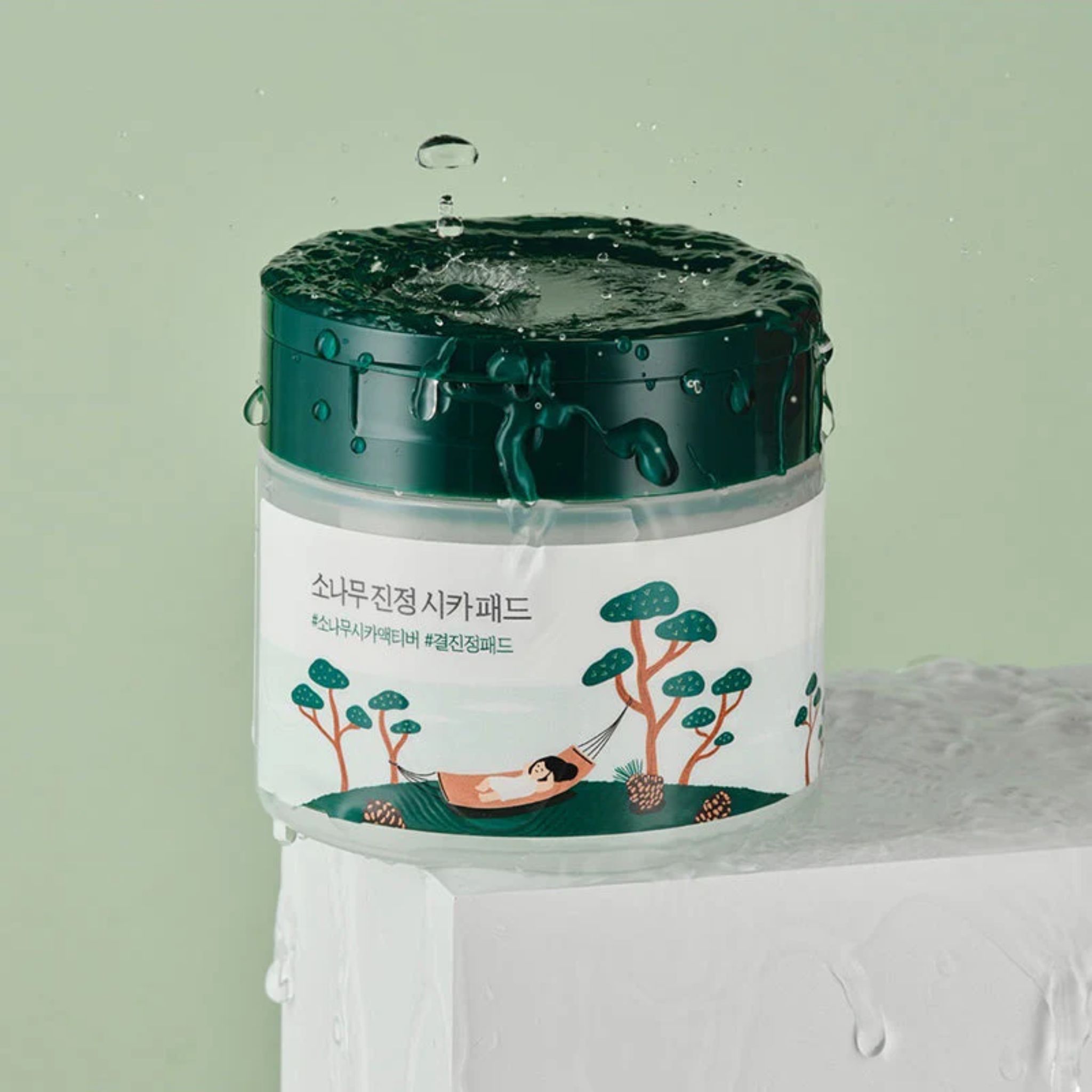 Round Lab Lab Pine Calming Cica Pad: contenitore con gocce d'acqua e motivo pino cica.