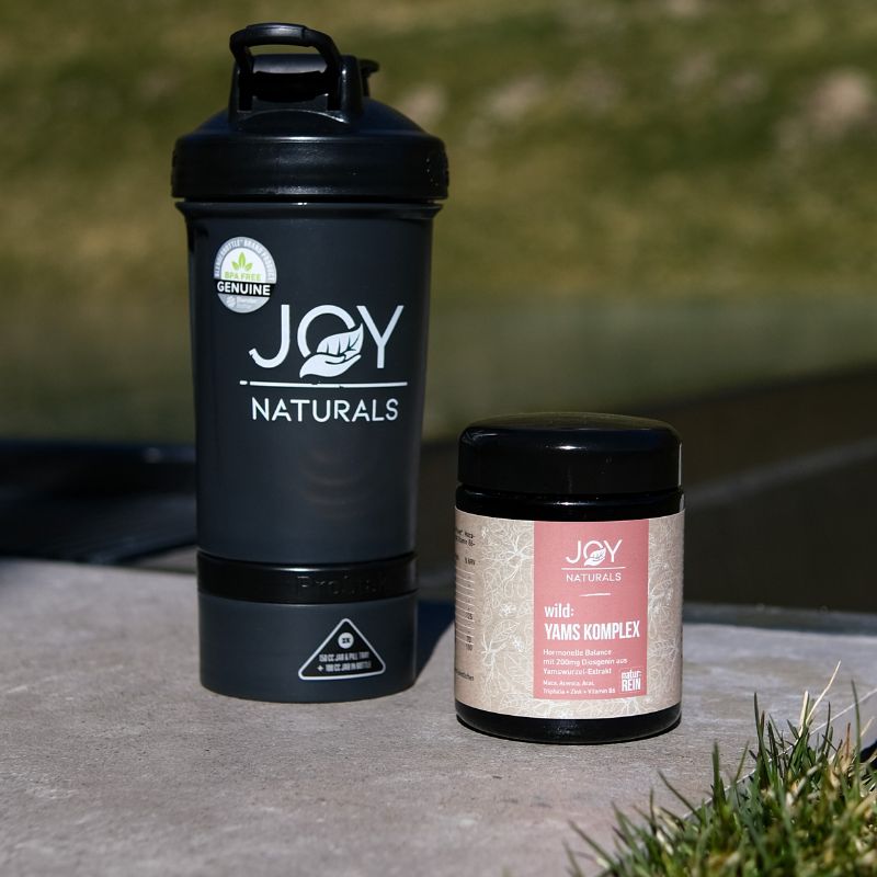 Prodotto JOY NATURALS accanto a uno shaker. Prodotto con etichetta rosa.