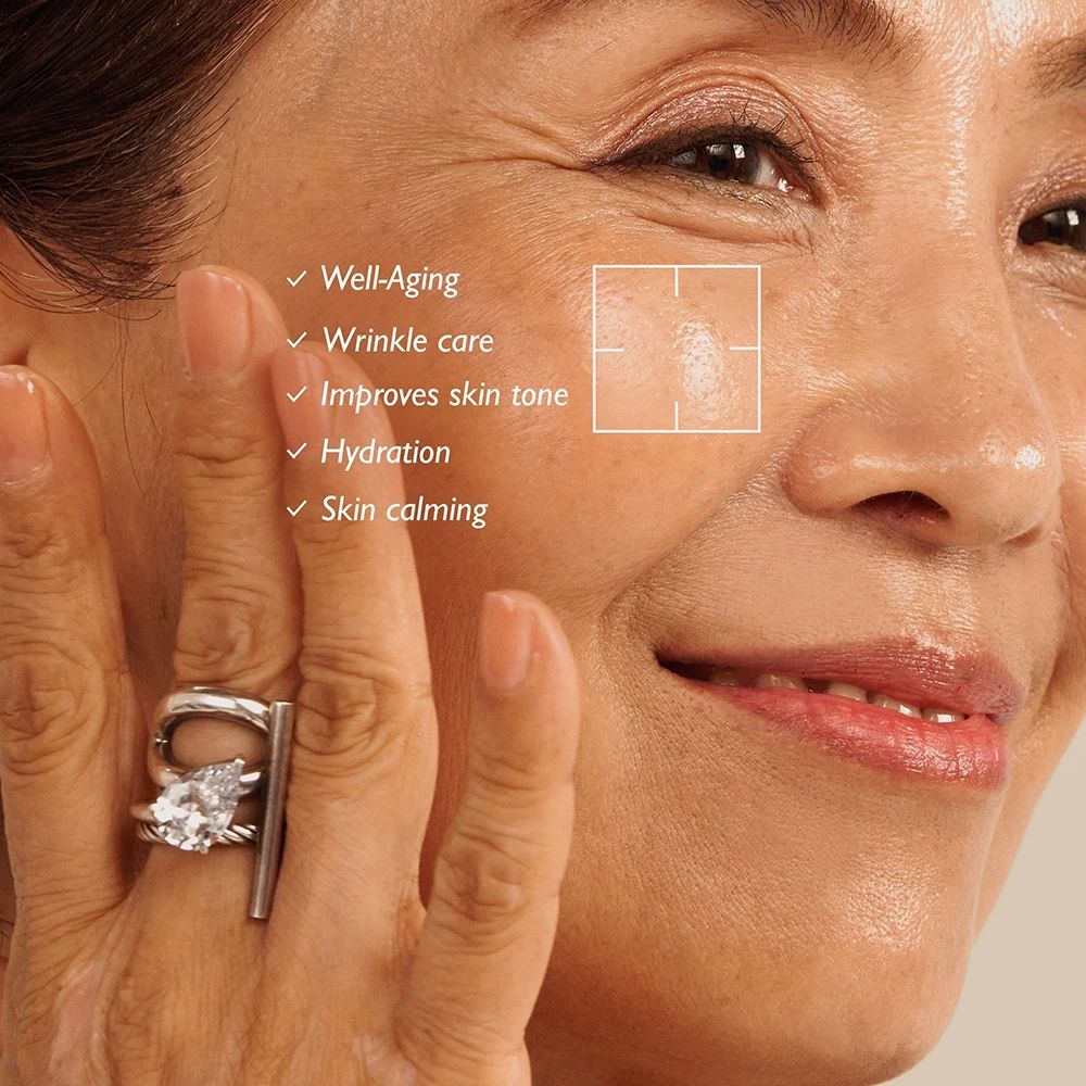 Primo piano di un viso con testo: Well-Aging, Wrinkle care, Improves skin tone, Hydration, Skin calming. Area della pelle evidenziata.